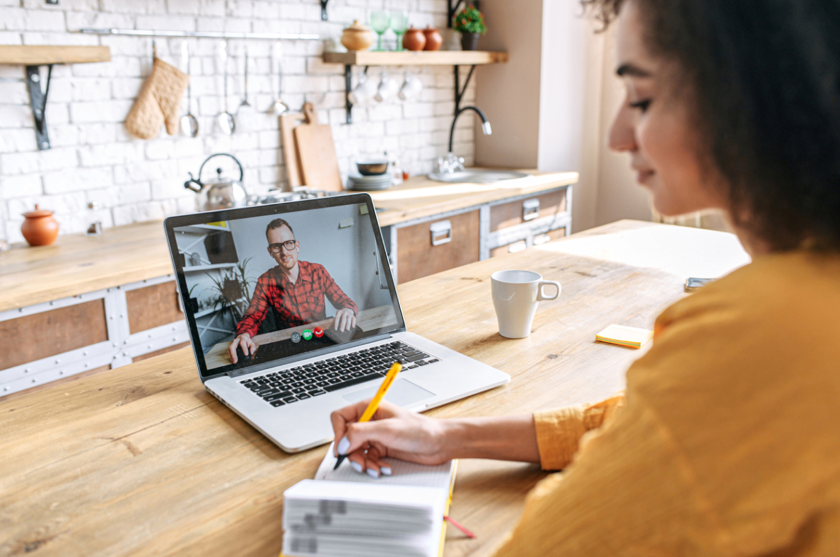 A woman in her kitchen is in a Zoom meeting with a man. 