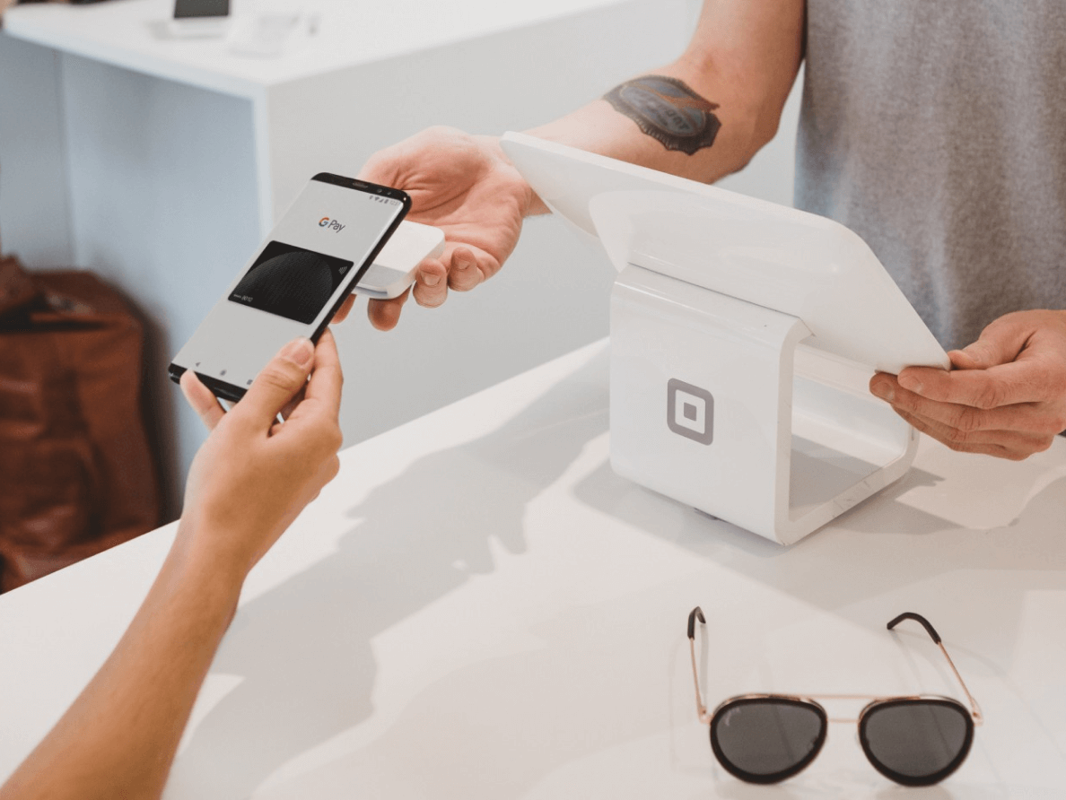 A person uses Google Pay on a smart phone at a retail terminal.