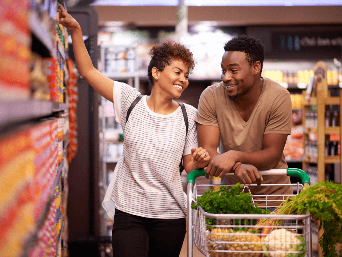 A smiling couple shop for groceries.