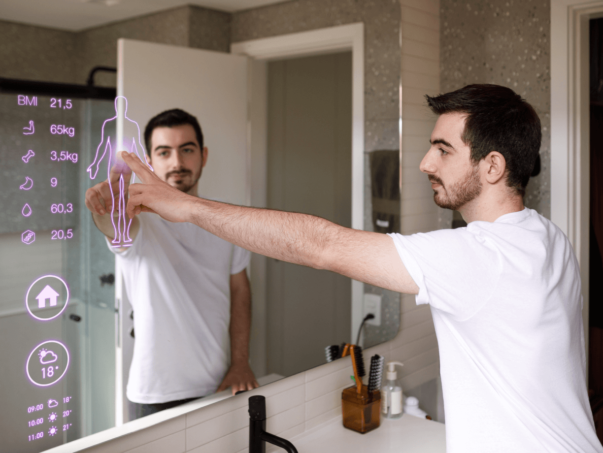 A man stands a bathroom counter and touches an icon on a smart mirror. 