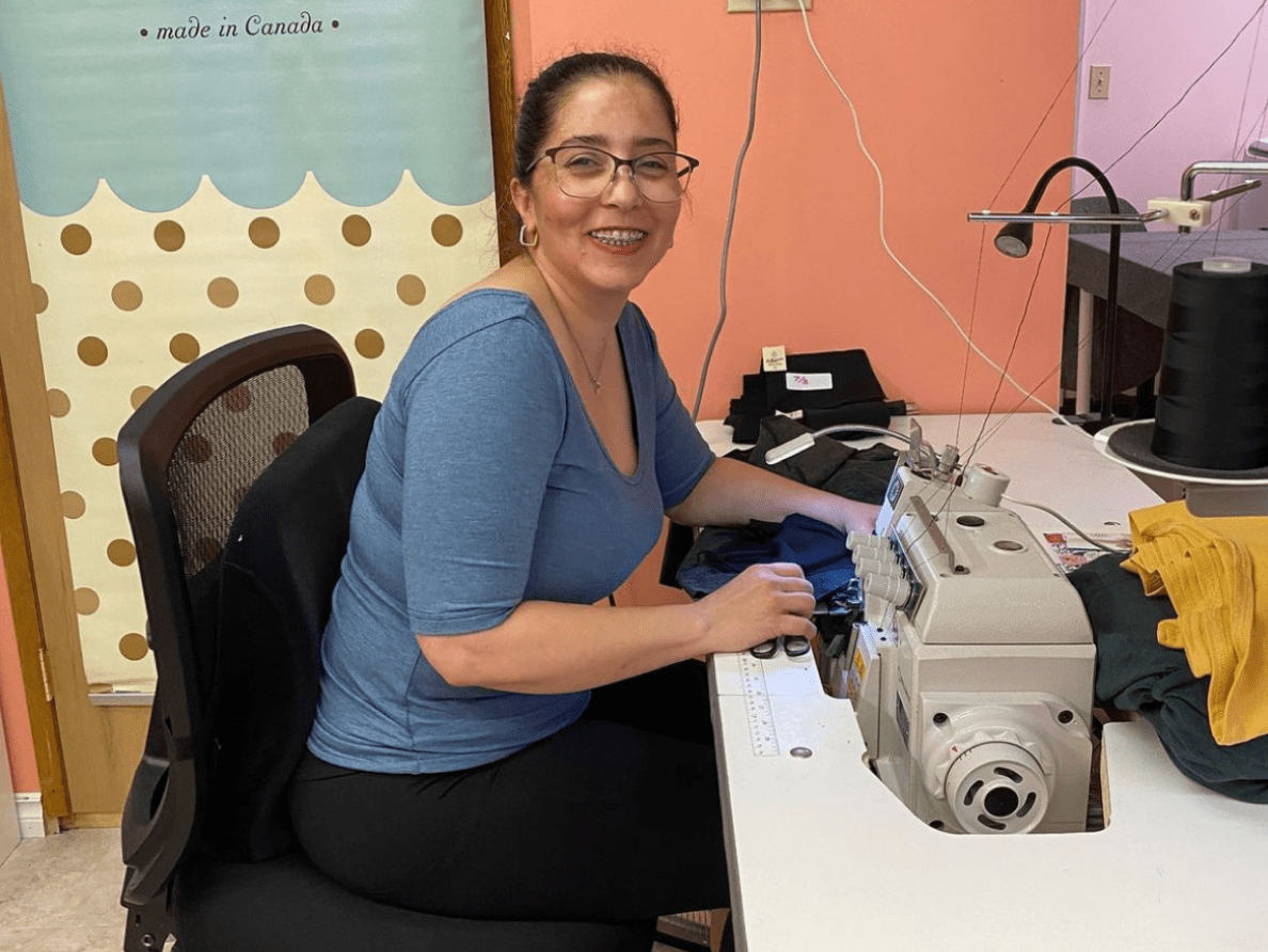 A seamstress for Buttercream Clothing sits at a sewing machine.