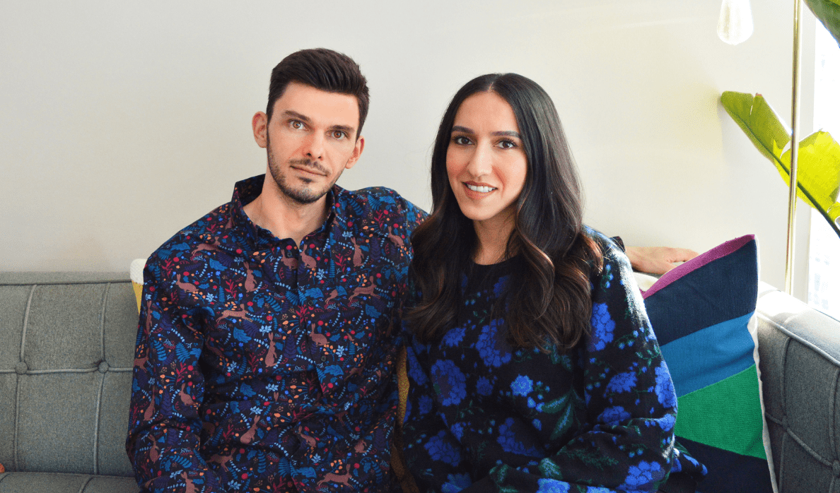 Antonio Krezic and his wife Shadi, co-founders of Poplin & Co., wear colourful tops from Poplin & Co. and sit together on a couch.