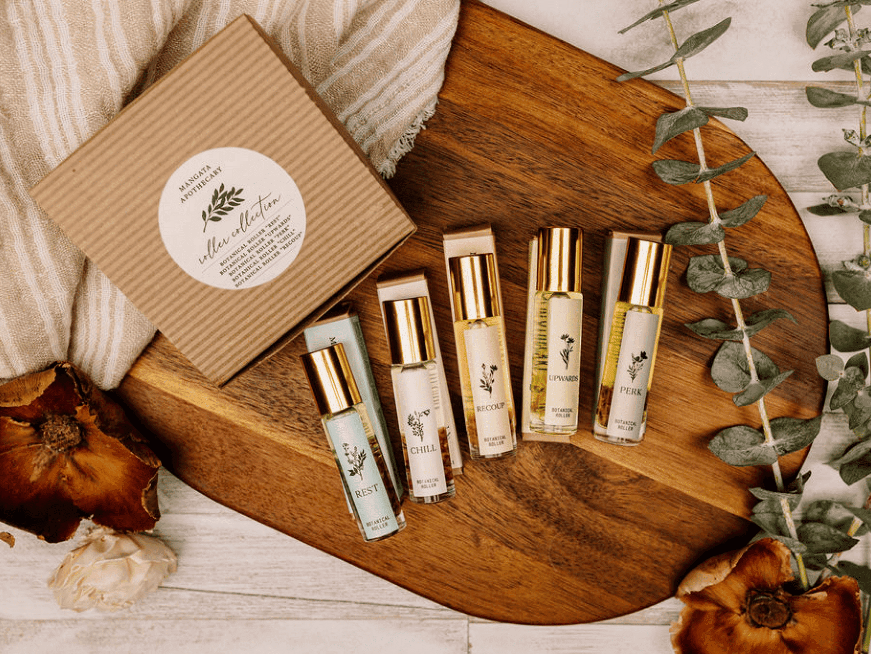 A collection of roller aromatherapy bottles from Mangata Apothecary sit on a wooden board.
