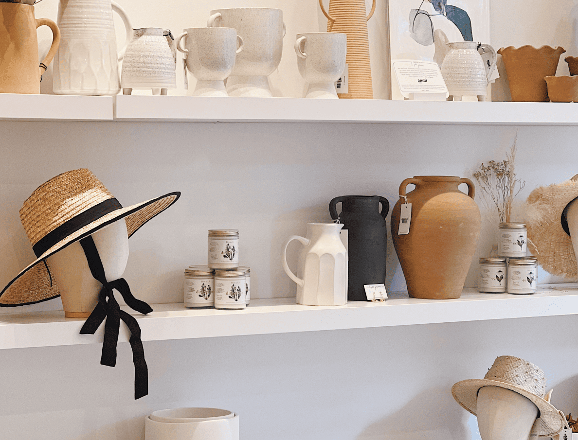 Shelves at Boutique 1861 filled with pottery and straw sun hats.