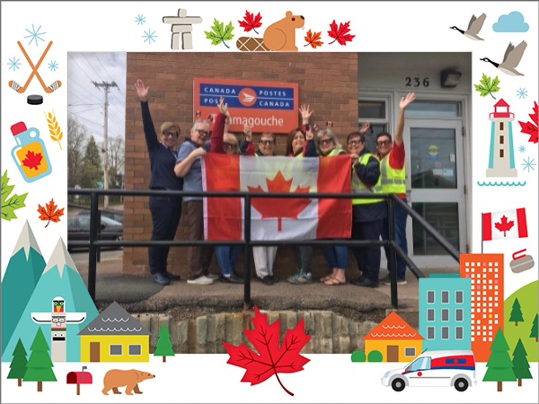 Group of Canada Post employee posing with a Canadian Flag outside of the Tamagouche Post Office in Nova Scotia. 