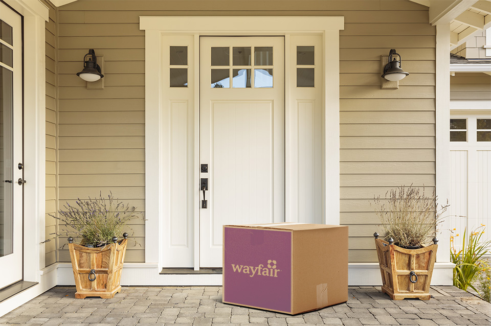 Boîte de wayfair.ca déposée devant la porte d’entrée blanche d’une maison