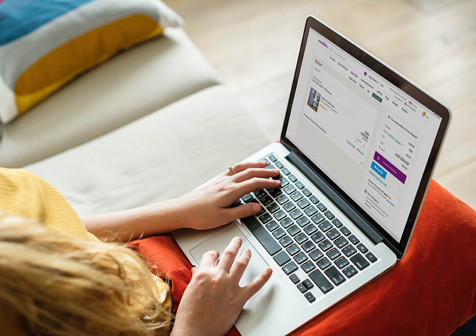 Caucasian woman’s hands on laptop keyboard. Laptop screen shows Wayfair.ca checkout page.