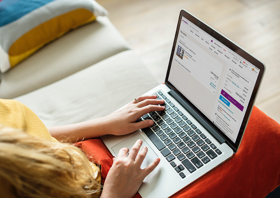 Mains d’une femme blanche sur un clavier d’ordinateur portable dont l’écran affiche la page Mon panier du site wayfair.ca