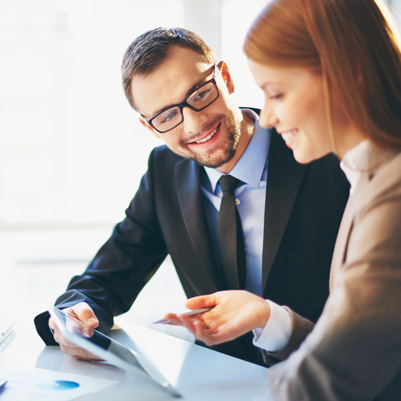 Deux employés comparant des notes et s’échangeant des idées en souriant. 