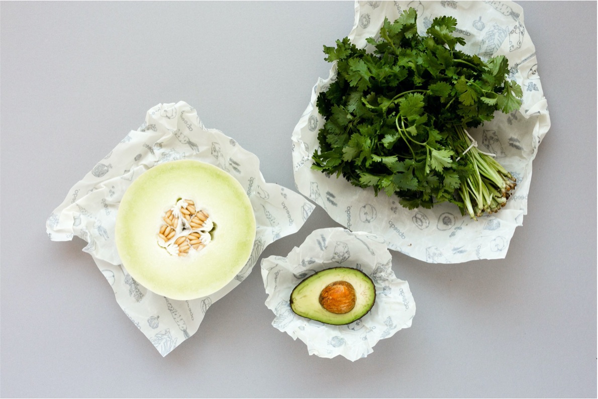 Half a honeydew melon and half an avocado sit on top of Abeego wraps. A bunch of parsley sits on an Abeego wrap.