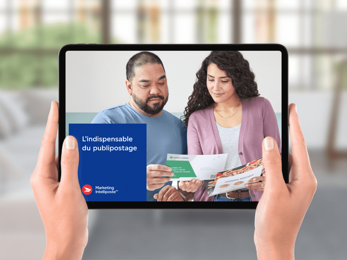 Les mains d’une femme tiennent une tablette sur laquelle est affichée la photo d’un couple et la mention « L’indispensable du publipostage ».