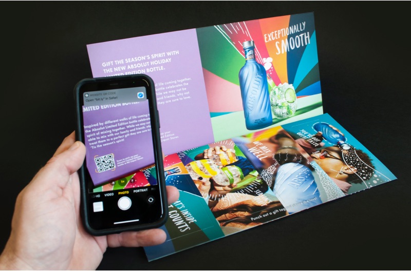 Une personne prend une photo d’un code QR imprimé sur un publipostage d’Absolut Vodka au moyen d’un téléphone cellulaire