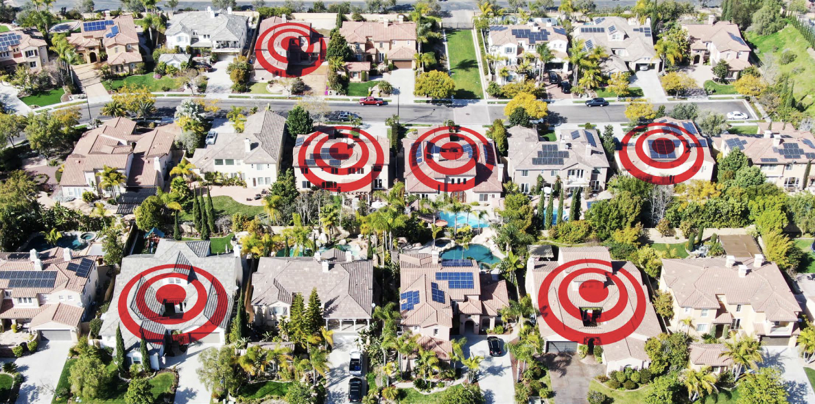 Point de vue aérien d’un quartier résidentiel avec des illustrations de cibles rouges sur certains toits.