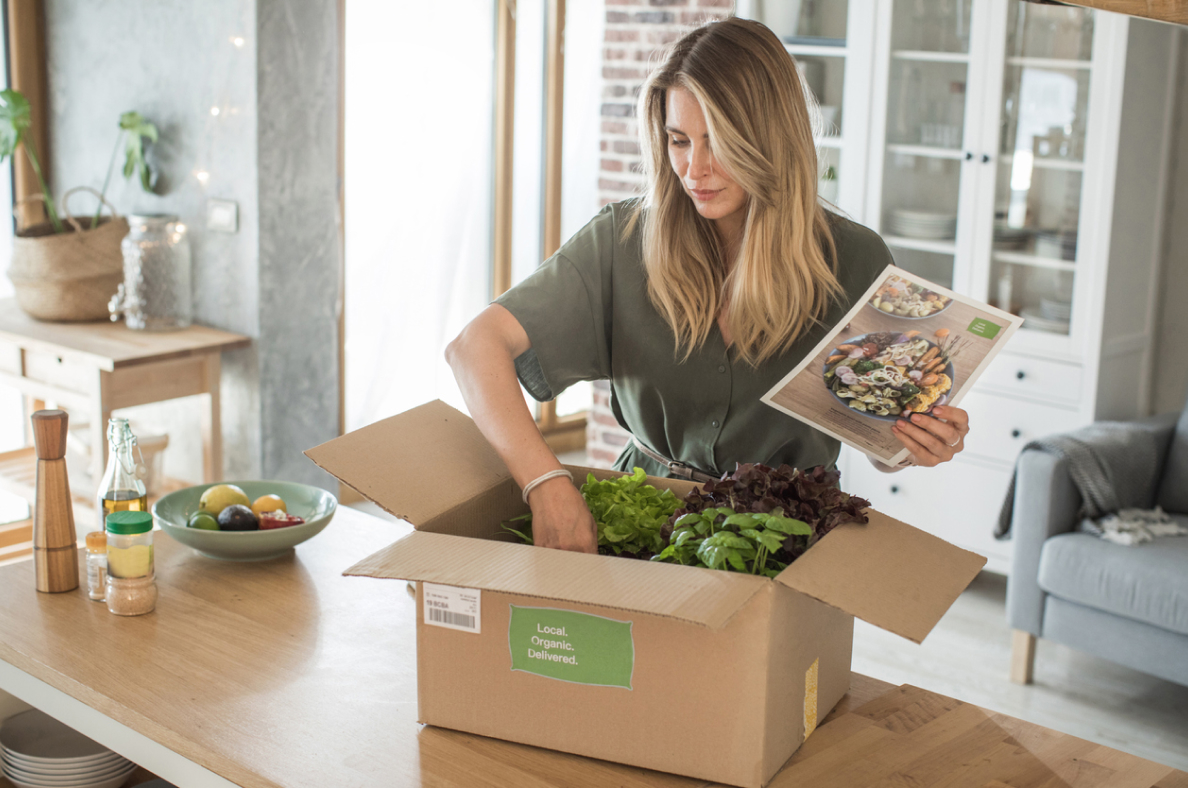 Une femme qui vide une boite de repas livrés à son domicile.