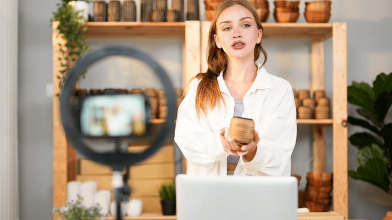 Dans une boutique d’artisanat, une jeune femme se fait filmer alors qu’elle tient une poterie à la main.