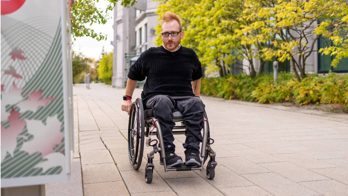 A man in a wheelchair approaches an accessible community mailbox.