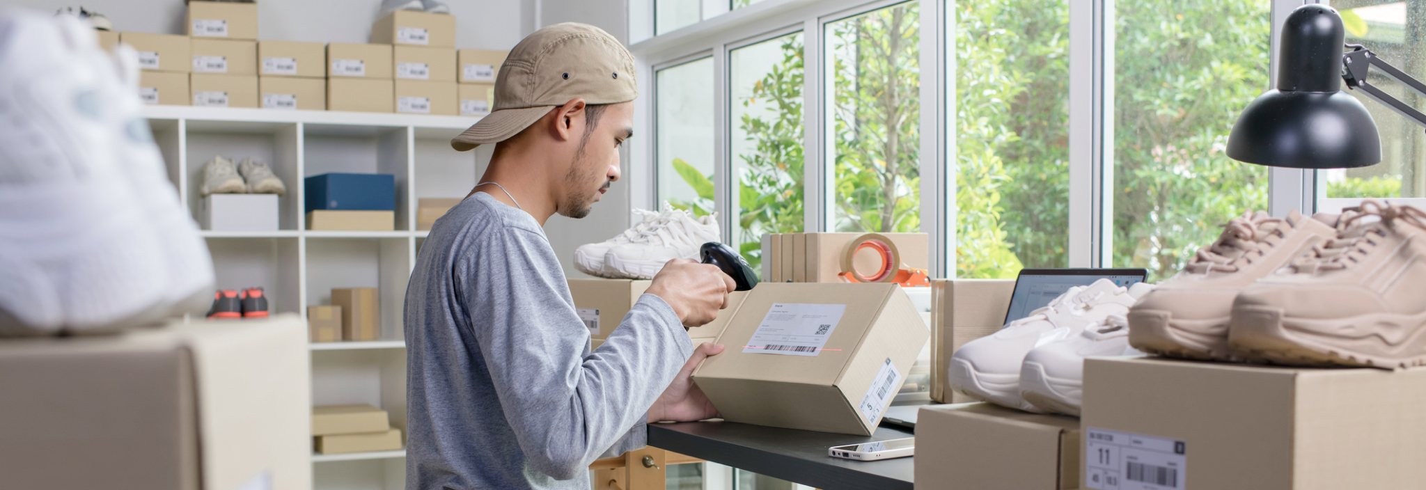 A young man scans a label on a shipping box in a room full of boxes.