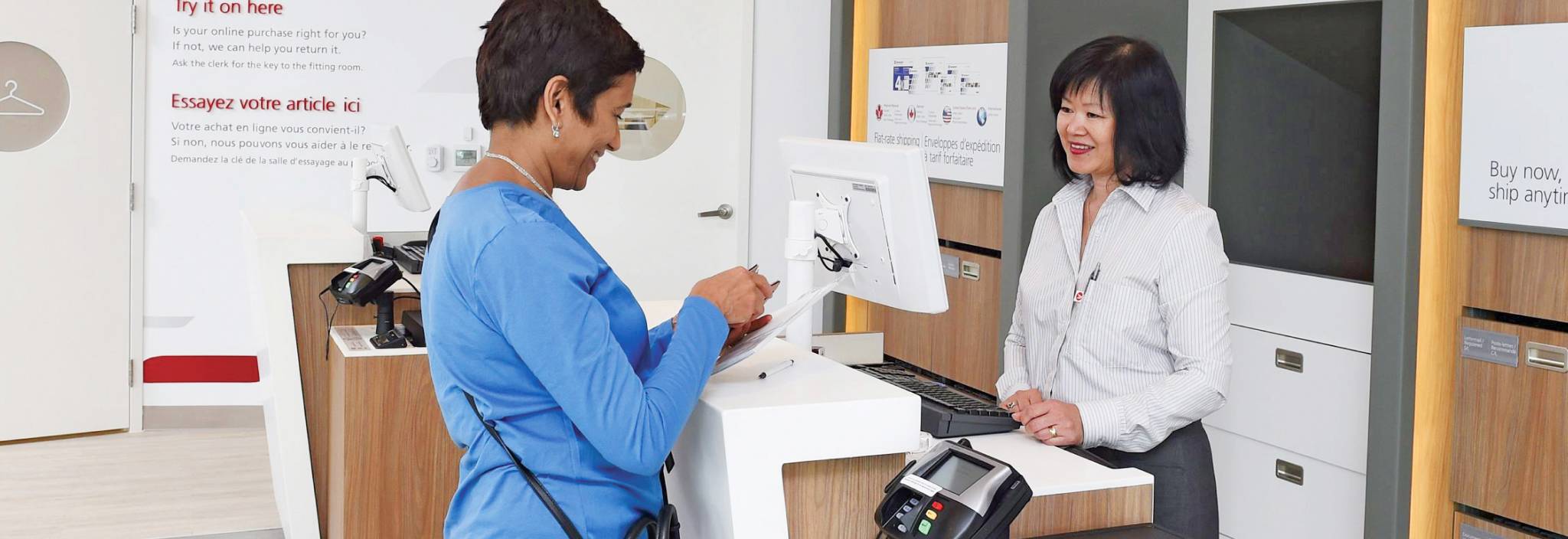 A woman completes her ID verification process at a Canada Post counter by presenting her government-issued photo ID.