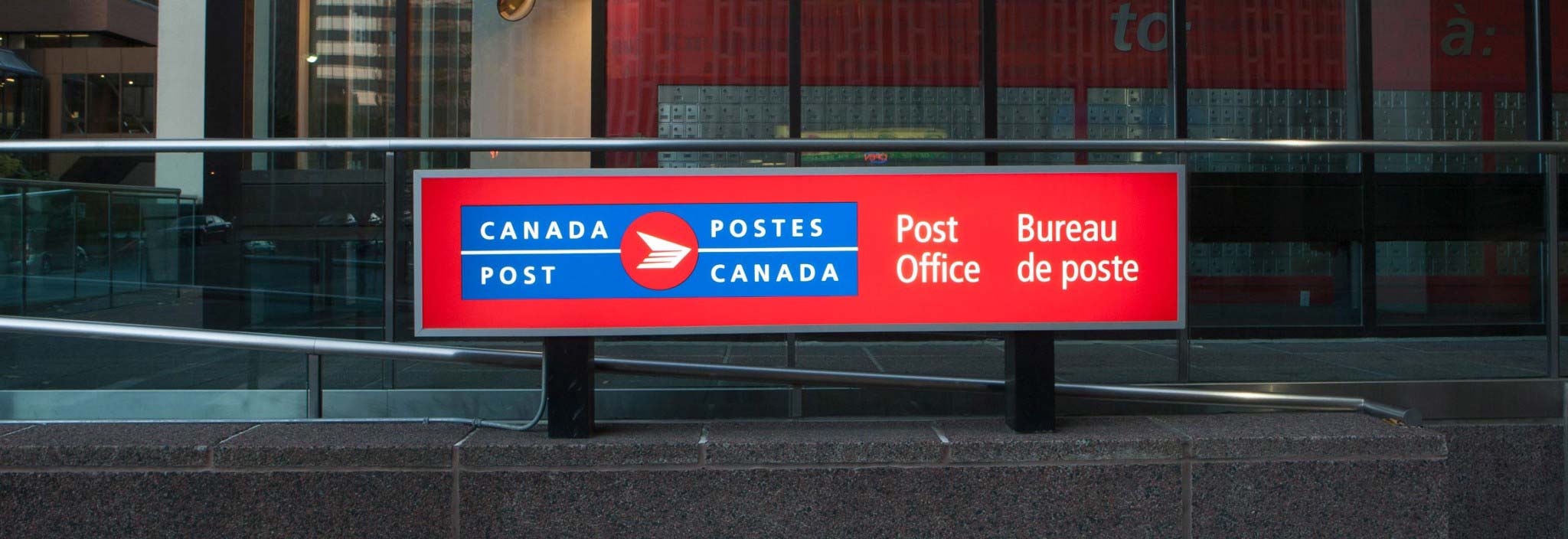 Close up of a large post office sign featuring the bilingual Canada Post logo