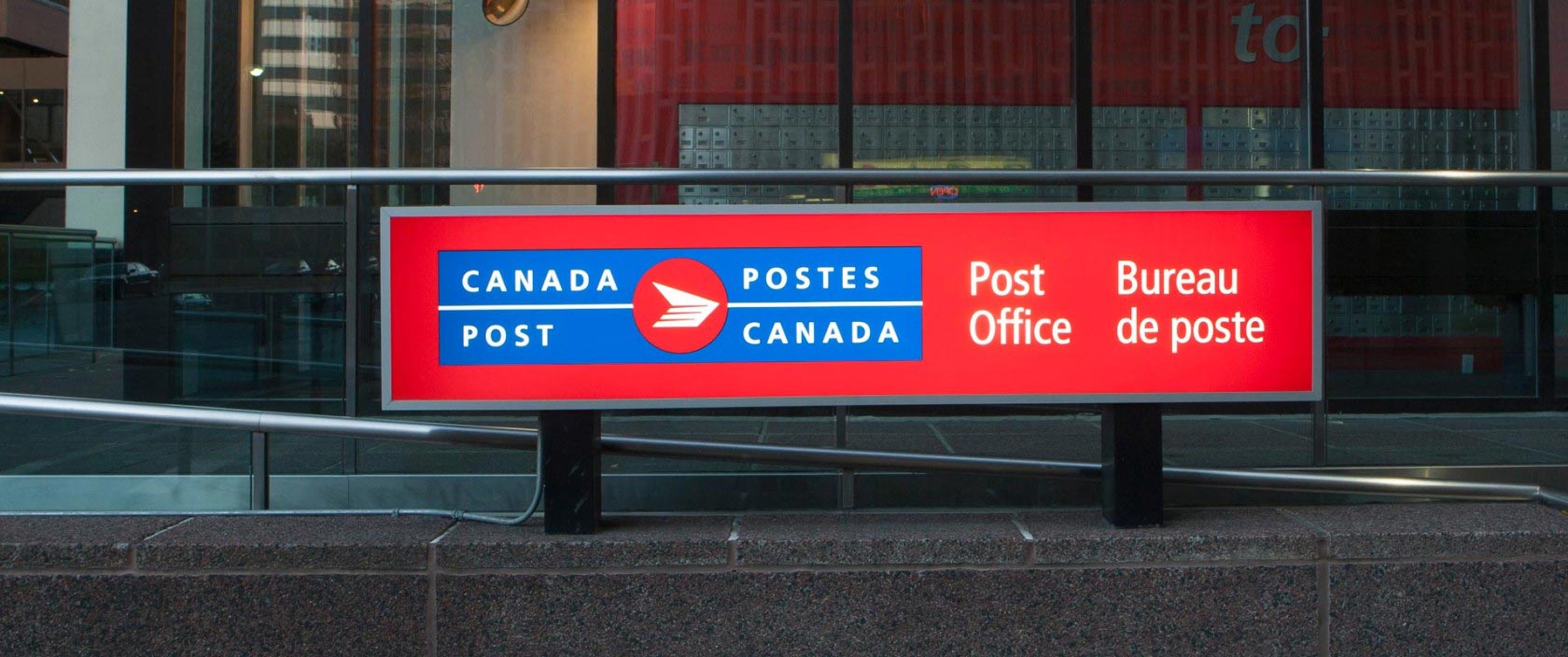 Close up of a large post office sign featuring the bilingual Canada Post logo