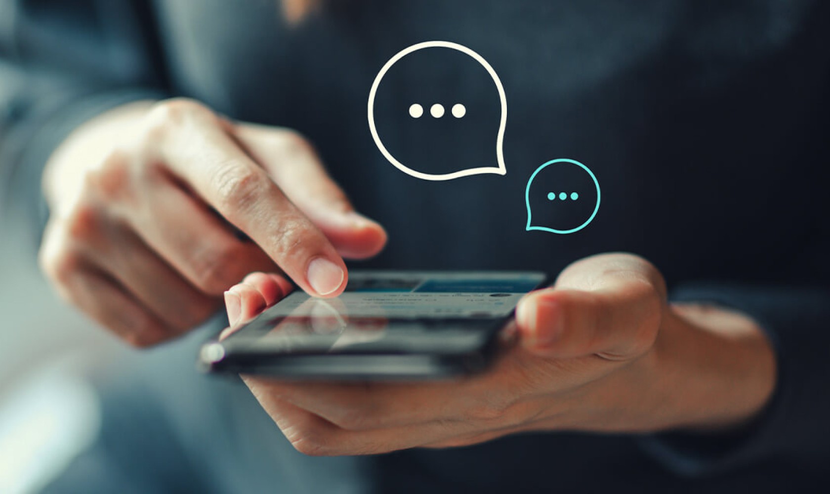 A person uses a smartphone. Chat bubbles containing ellipses are superimposed over the image.