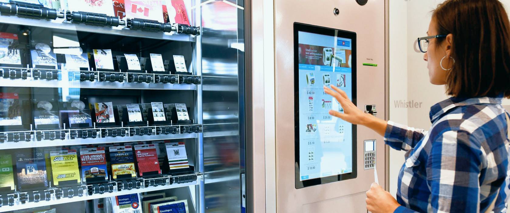 A woman uses a touchscreen to purchase a gift card from a Canada Post self-serve vending machine.