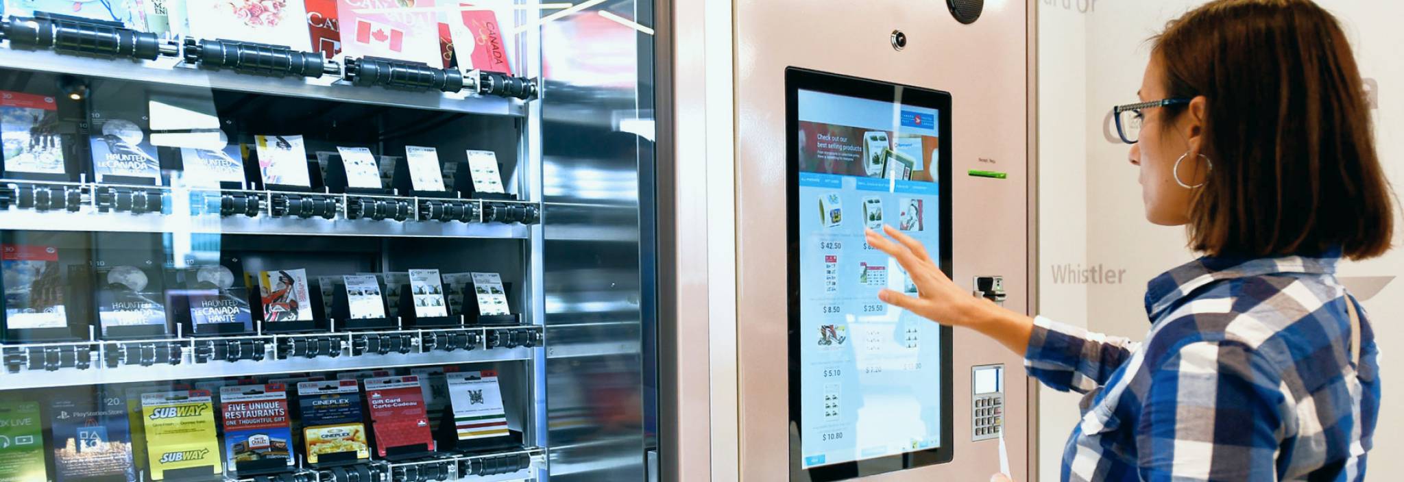 A woman uses a touchscreen to purchase a gift card from a Canada Post self-serve vending machine.