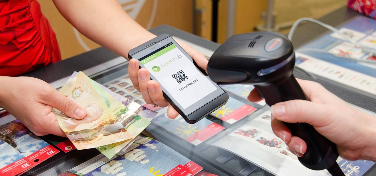 A woman makes a cash payment by presenting her Loadhub QR code at a Canada Post counter.