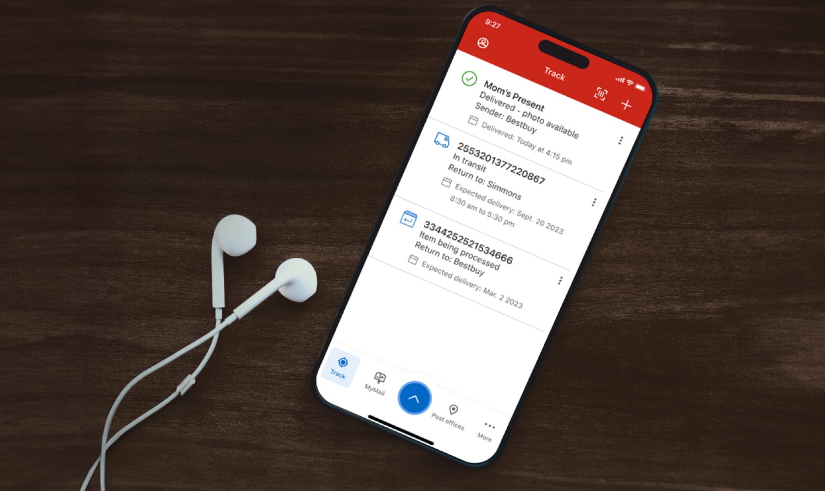 A cellphone is used to track multiple shipments in the Canada Post app. Earbuds rest beside the phone.