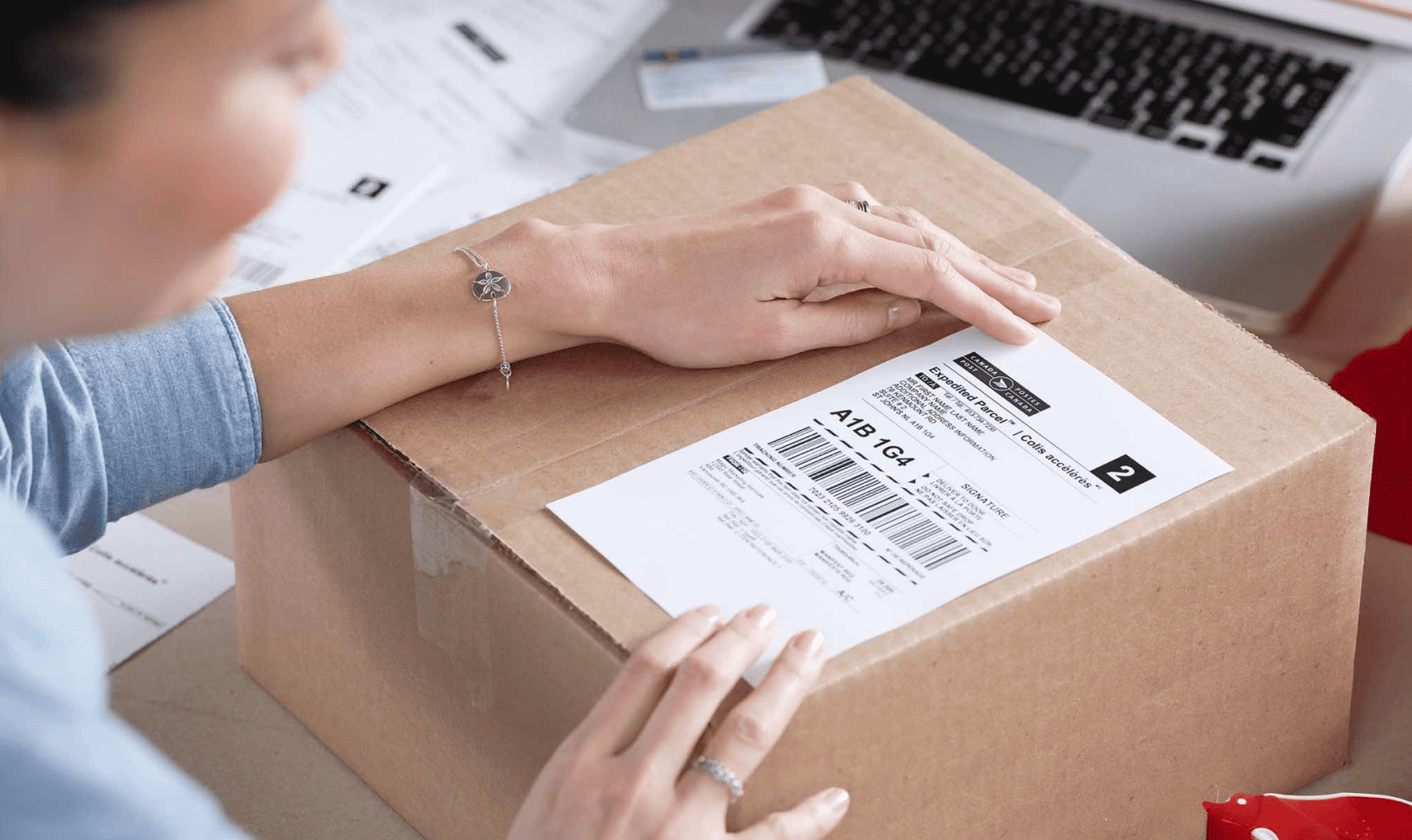 Woman applies a Canada Post return label to a package.