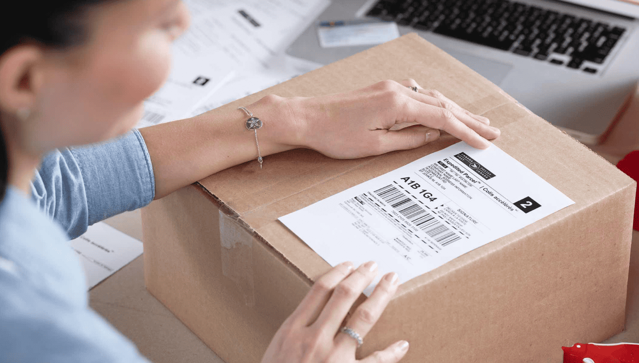Woman applies a Canada Post return label to a package.