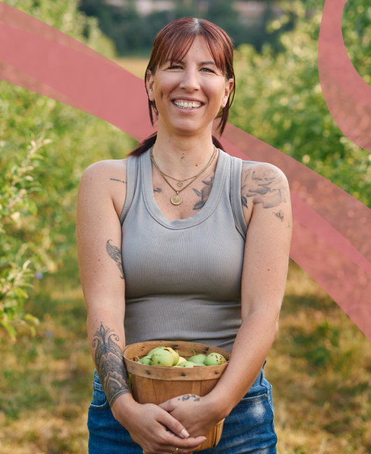 Vian Nguyen, Founder of Rude Mama Hotsauce, smiles and sits beside a spread of her products.