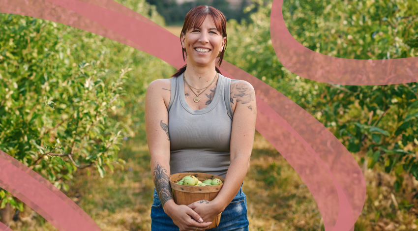 Vian Nguyen, Founder of Rude Mama Hotsauce, smiles and sits beside a spread of her products.