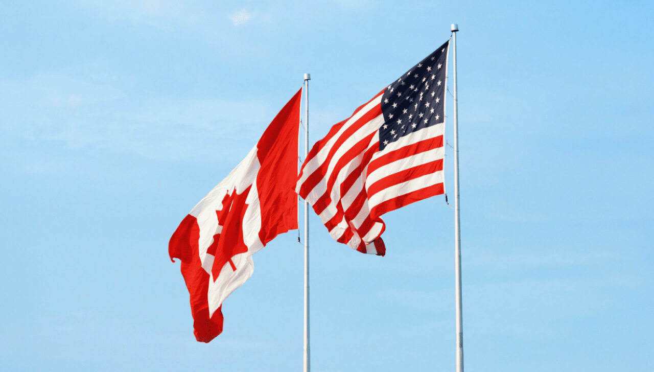 A Canadian flag and an American flag wave in the breeze.