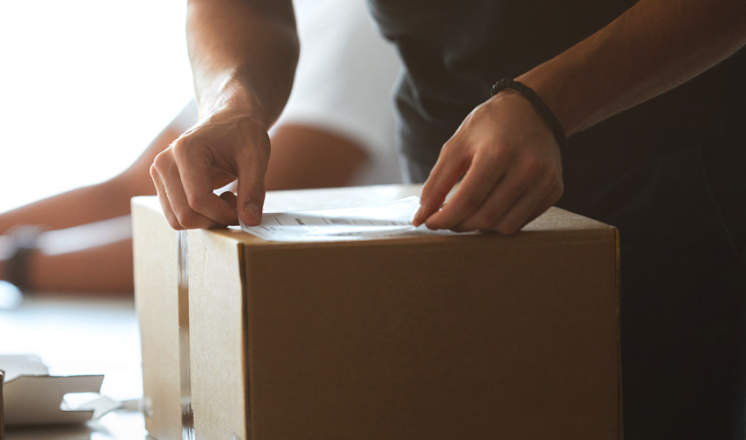 A man places a shipping label on a cardboard box.