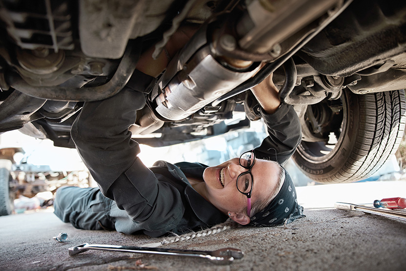 Une femme souriante regarde un écran d’ordinateur portable.