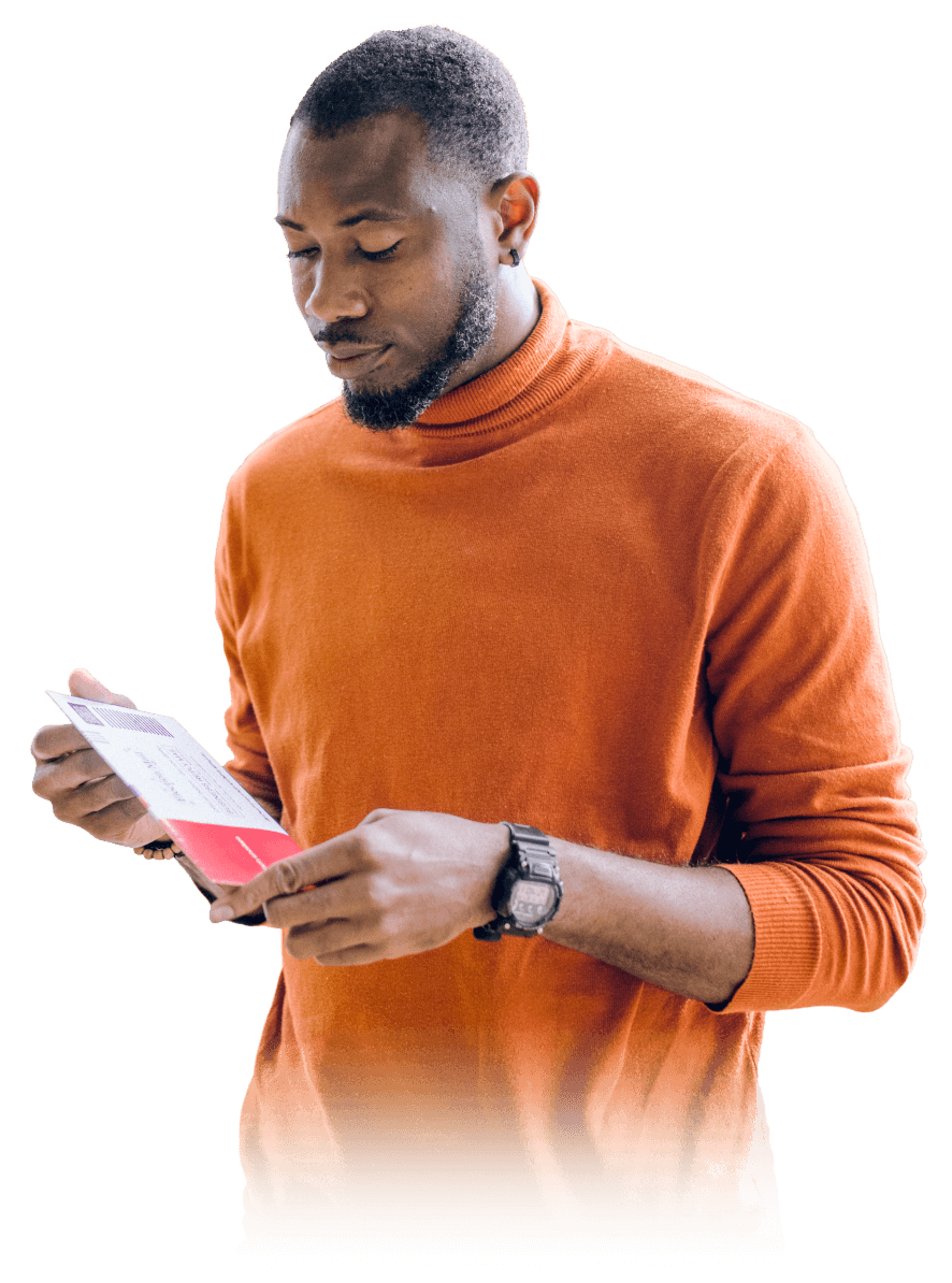 A man in an orange turtleneck sweater reads a colourful flyer.