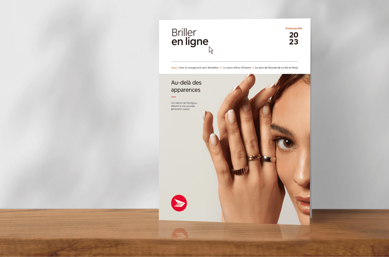 La page couverture de l’édition printemps/été du magazine « Briller en ligne » affichant le visage d’une femme et ses deux mains, dont l’une porte trois anneaux.