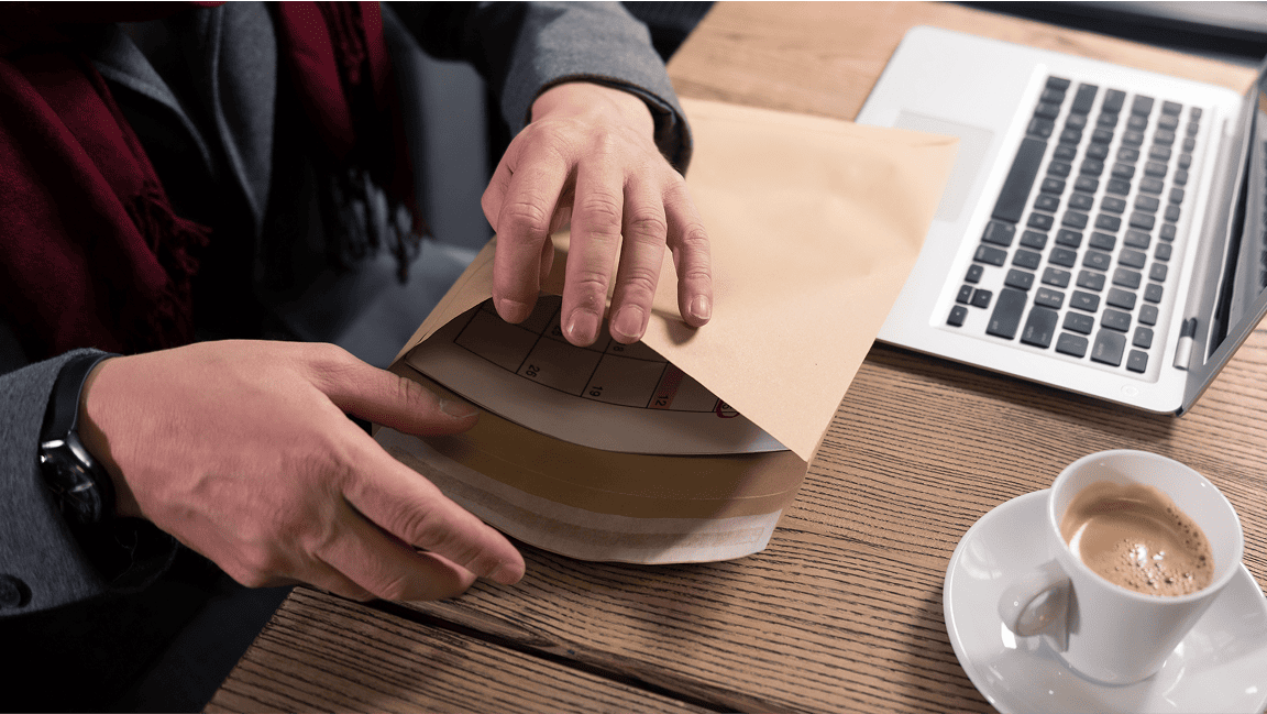 A man places documents into an envelope for shipping.