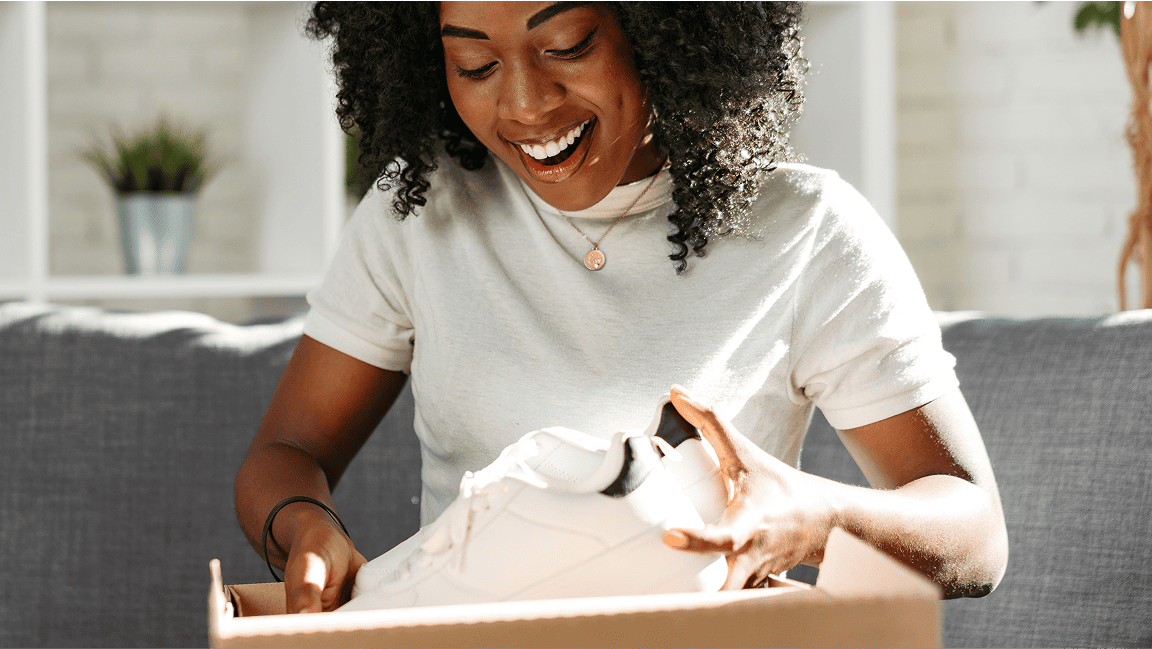 A woman smiles as she packs a gift into a shipping box.