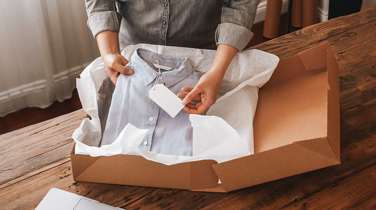 Person placing a folded shirt with tag into shipping box