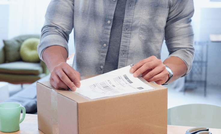 A man places a shipping label on a cardboard box.