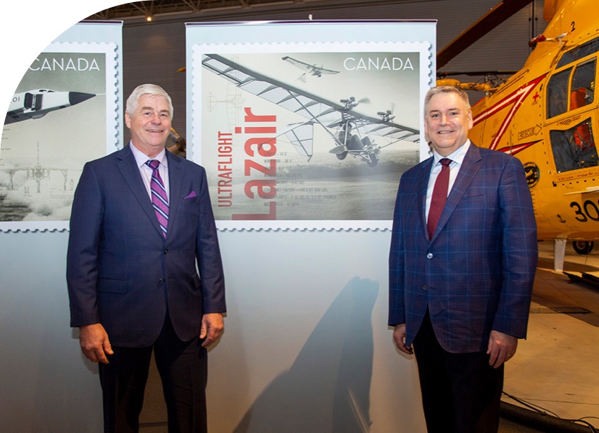 Dale Kramer et Doug Ettinger dévoilent un des timbres de l’émission Exploits de l’aviation canadienne, sur le Lazair.