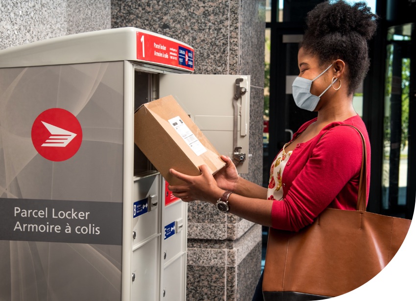 A woman wearing a mask retrieves a parcel from a Canada Post parcel locker.