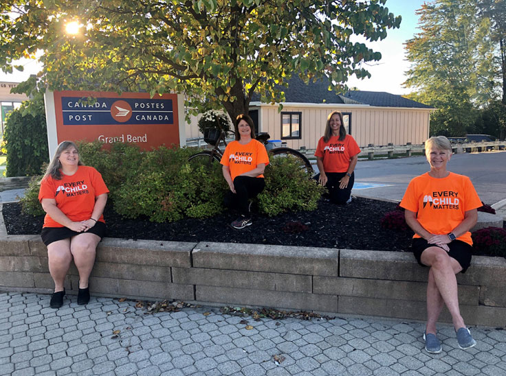 Canada Post employees Kathy Hutchinson, Lisa Merner, Andra Brand and Darlene Rumford wear orange shirts to show their support for Orange Shirt Day.