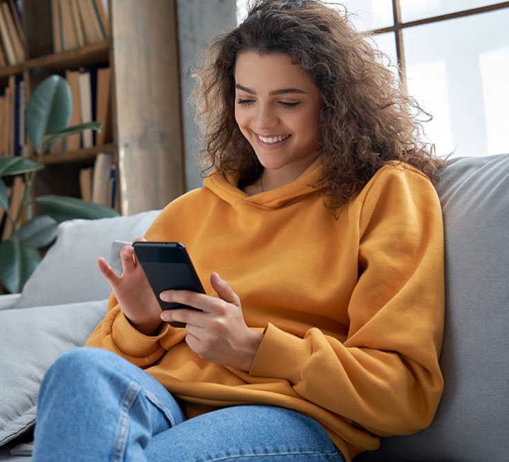 A Canada Post customer sits on a couch and tracks a parcel on her mobile phone.