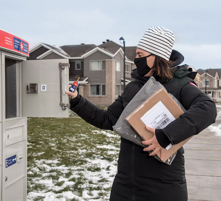 Une cliente de Postes Canada récupère des colis dans un casier à colis extérieur à Stittsville, en Ontario