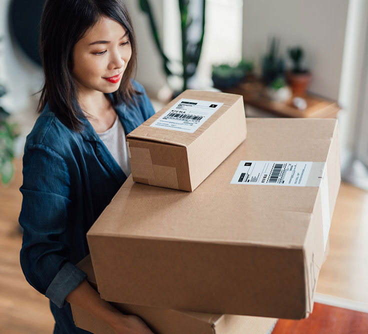 An ecommerce business owner carries a stack of parcels ready for shipment.