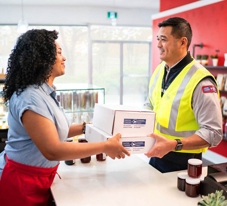 A Canada Post employee delivers parcels to a Canadian business owner.