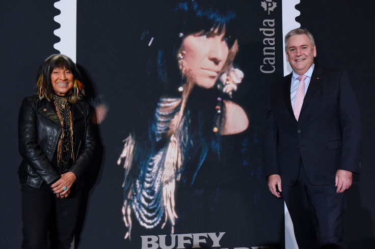 Buffy Sainte-Marie, auteure-compositrice-interprète, en compagnie de Doug Ettinger, président-directeur général de Postes Canada, lors du dévoilement du timbre rendant hommage à l’artiste